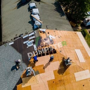 Home-Roof A roofing contractor skillfully repairing a roof under a clear blue sky, showcasing their expertise and hard work.