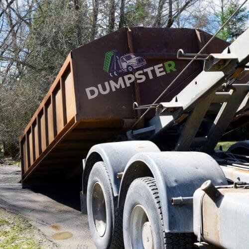 Roll-Off Dumpster Roll-off dumpster being unloaded from a truck for waste disposal services in an outdoor setting.